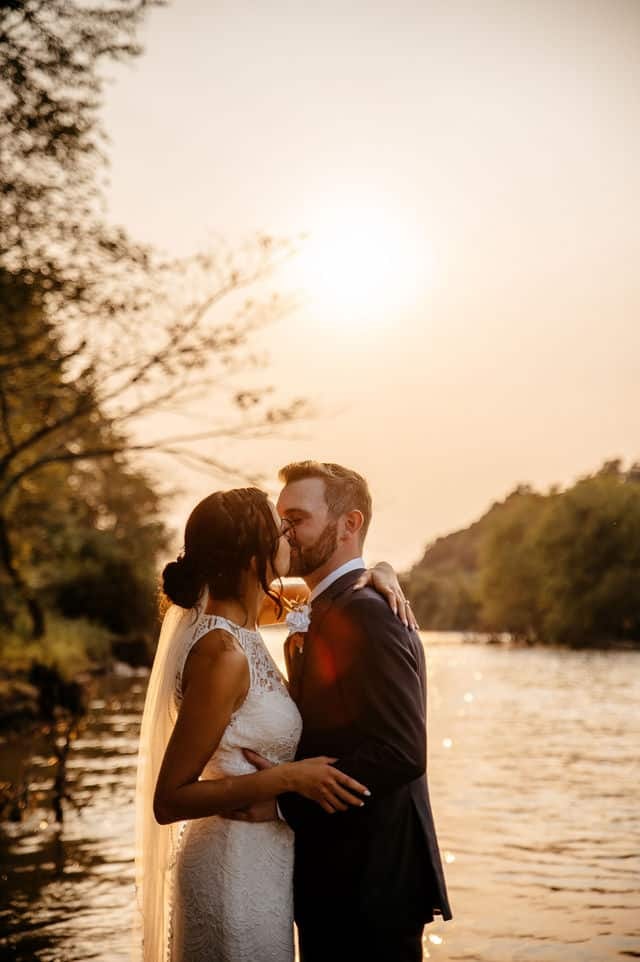 Wedding pic of the wife and groom by the lake kissing