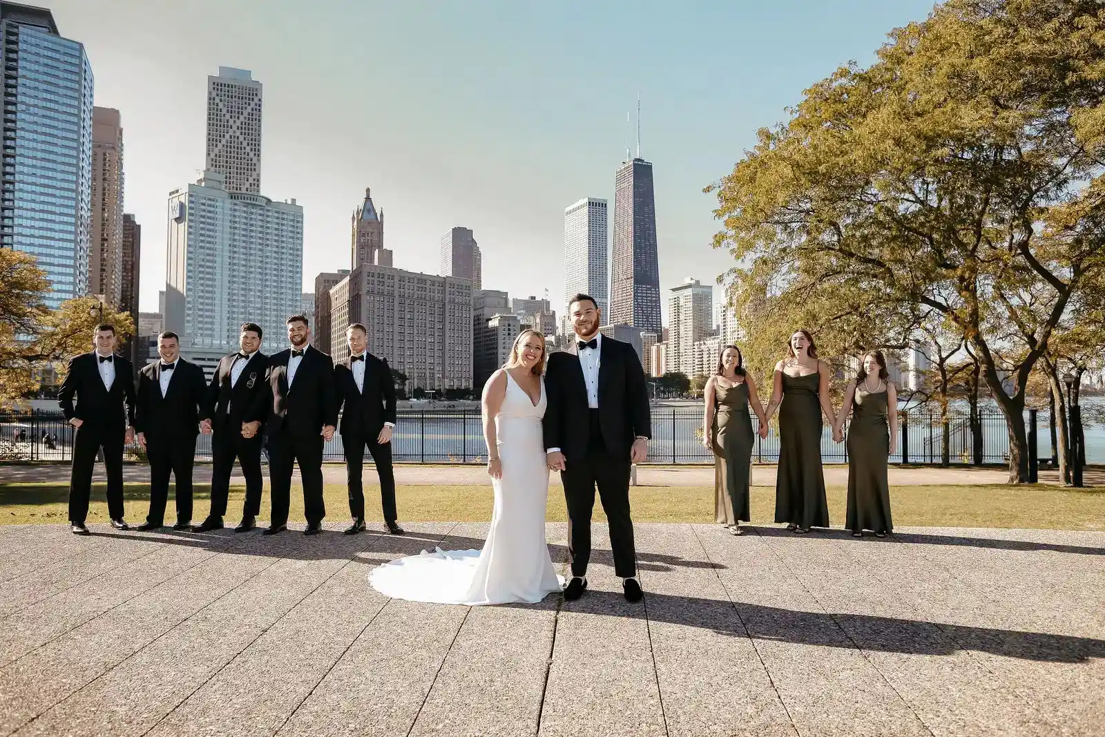 Bride, groom, and wedding party posing in front of a city skyline during a Georgia wedding photography session.